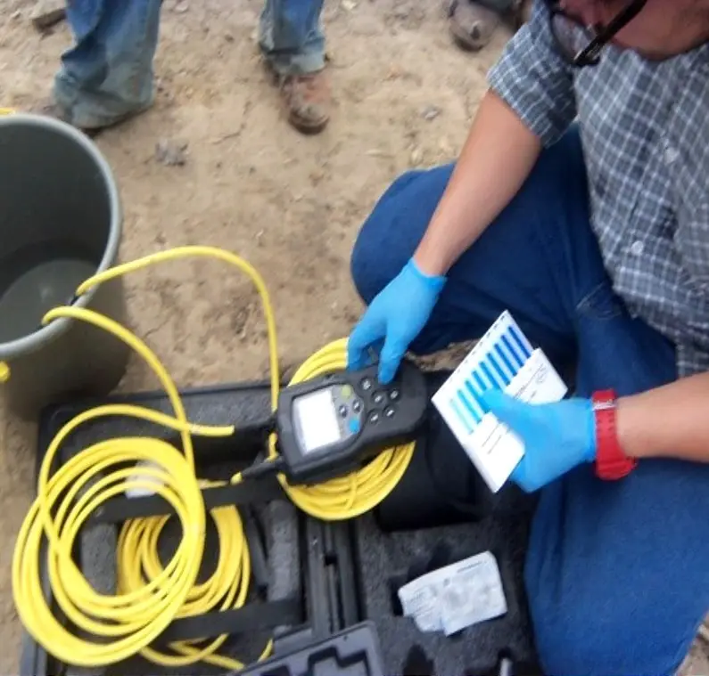 Técnico con guantes calibra un multiparámetro de campo junto a la sonda